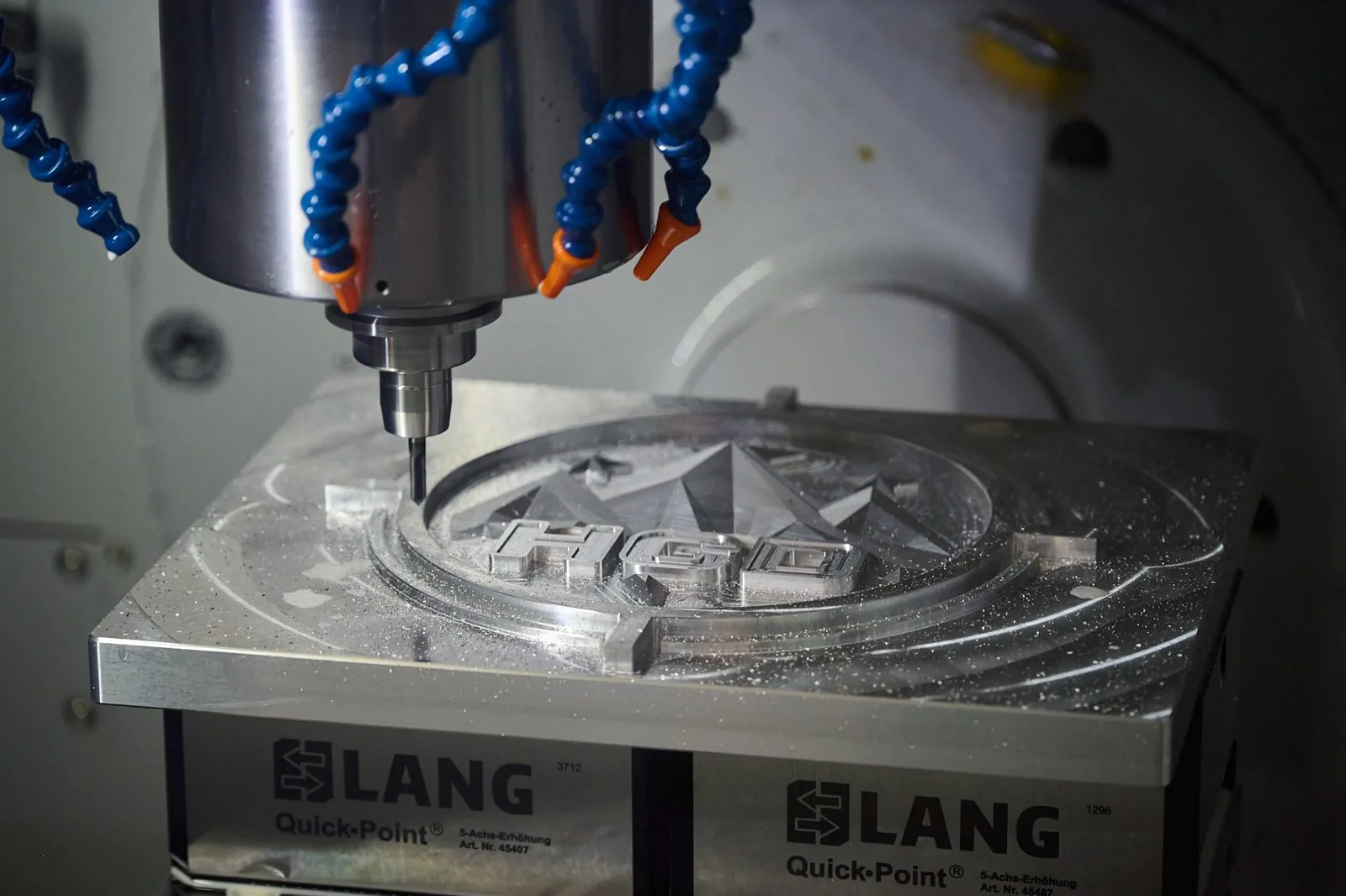 A CNC mill cutting the High Ground Defense star mark into an aluminium fixture plate.
